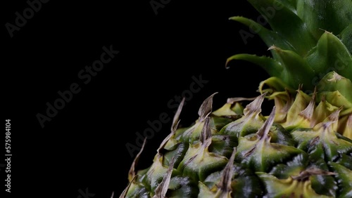 Α delicious pineapple fruit rotating in a diagonal direction on the right side against a black background.