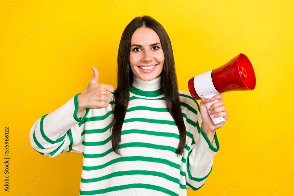 Photo of sweet confident woman wear striped sweater rising thumb up loudspeaker isolated yellow color background Photo of sweet confident woman wear striped sweater rising thumb up loudspeaker isolated yellow color background