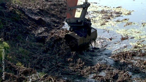 excavator dredge is dredging, working on river, canal, deepening and removing sediment, mud from riverbed in a polluted waterway.
Large excavators engaged in cleaning of the riverbed of a river from t photo