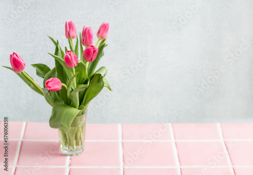 Spring emote table background.  vase with pink tulips with space. Home interior decoration, minimalist design or springtime holidays. 