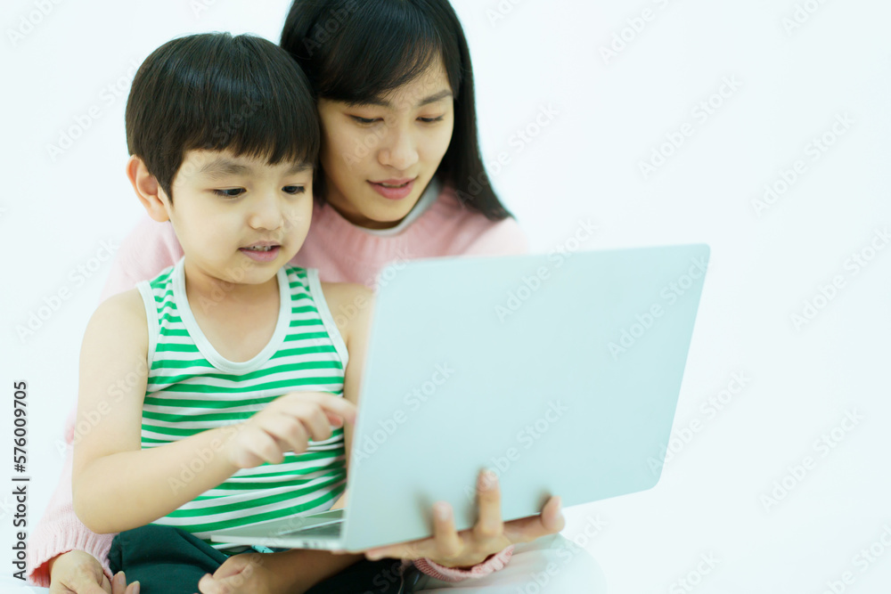 Happy Asian little young boy learning on laptop computer or notebook with his mother while stay at home in weekend. Happy Asian little young boy learning on laptop computer or notebook with his mother while stay at home in weekend.