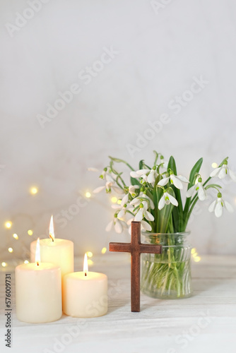 Fototapeta Naklejka Na Ścianę i Meble -  Wooden cross, snowdrops flowers and candles on table, blurred abstract background. Religious church holiday. symbol of faith in God, Christianity Feast, Easter, Palm Sunday, Lent