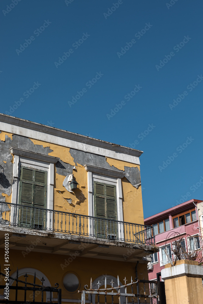 Obraz premium Shabby yellow facade with windows closed by shutters.