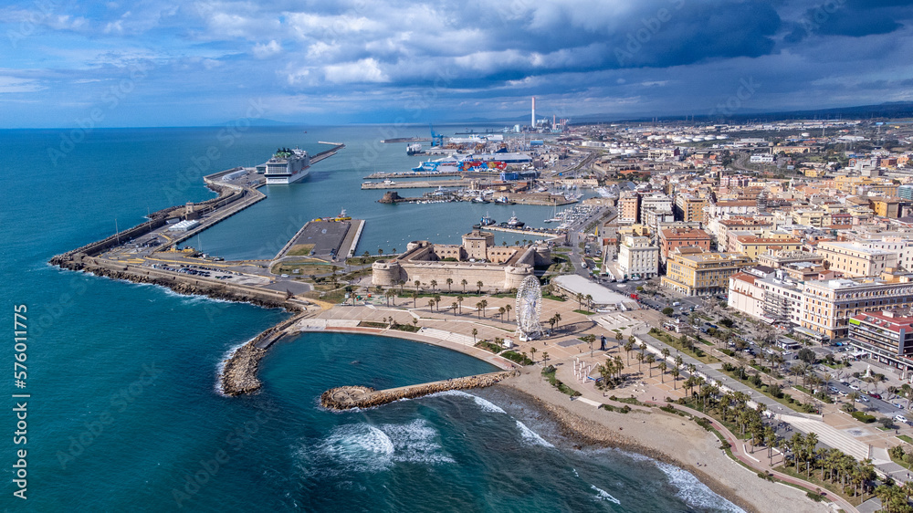 Fototapeta premium Panoramic view of the city of Civitavecchia with the adjoining tourist port and Forte Michelangelo. Emerald sea and view with tropical palm trees. Ferris wheel and cloudy sky.
