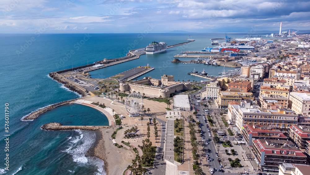 Panoramic view of the city of Civitavecchia with the adjoining tourist port and Forte Michelangelo. Emerald sea and view with tropical palm trees. Ferris wheel and cloudy sky.