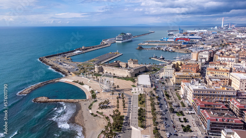Panoramic view of the city of Civitavecchia with the adjoining tourist port and Forte Michelangelo. Emerald sea and view with tropical palm trees. Ferris wheel and cloudy sky. © Tommaso