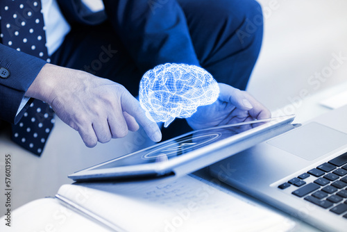 Businessman touching the brain working of Artificial Intelligence (AI) on Tablet, futuristic business and coding software development concept.