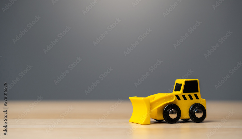 The yellow bulldozer toy. Construction works. Clearing and leveling the land. Building destruction. Take down Illegal construction. Industry The yellow bulldozer toy. Construction works. Clearing and leveling the land. Building destruction. Take down Illegal construction. Industry