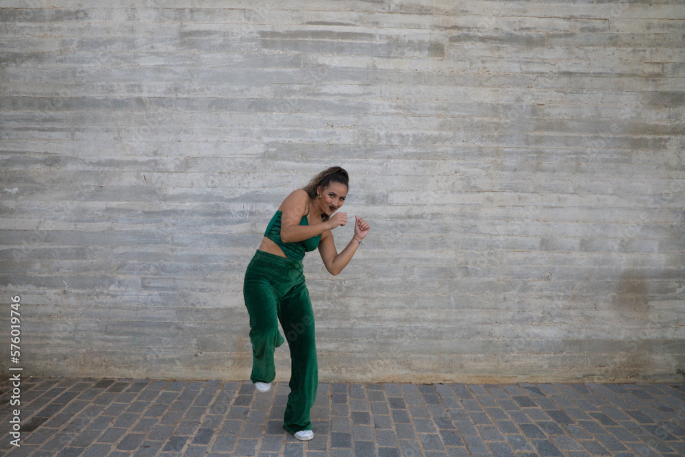 Latin woman, young and beautiful dancing modern dance on gray cement background. Woman kicks in the air. Modern dance and dance concept. Latin woman, young and beautiful dancing modern dance on gray cement background. Woman kicks in the air. Modern dance and dance concept.