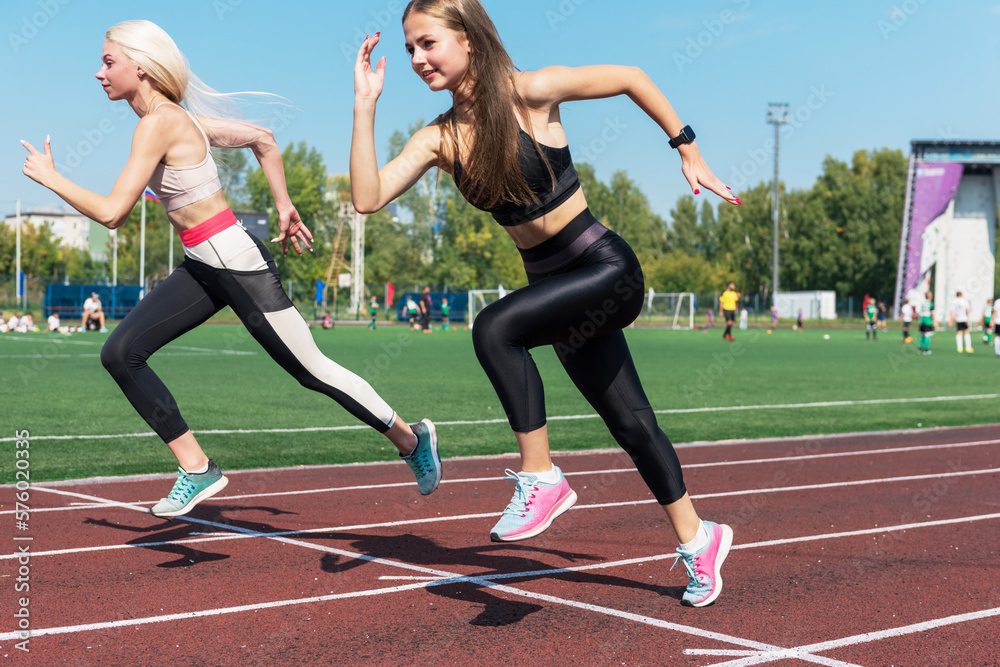 Two athlete young woman runnner on the start at the stadium outdoors