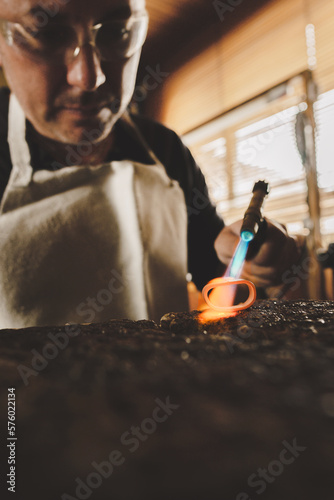artisan man in the process of manufacturing a jewel molding ring with fire in his workshop. High quality photo
