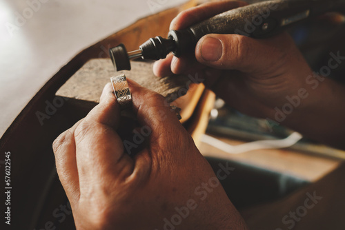 closeup of hands of male craftsman jeweler in the process of making a ring in his workshop. High quality photo