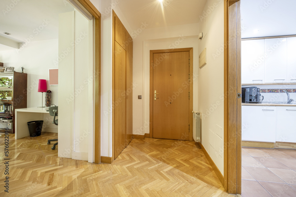 Entrance hall of a house with an oak access door with golden safety hinges, wooden carpentry of the same material and oak parquet floors