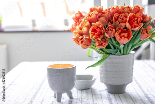 Spring composition with a bouquet of orange tulips in the interior of the house. #576023915