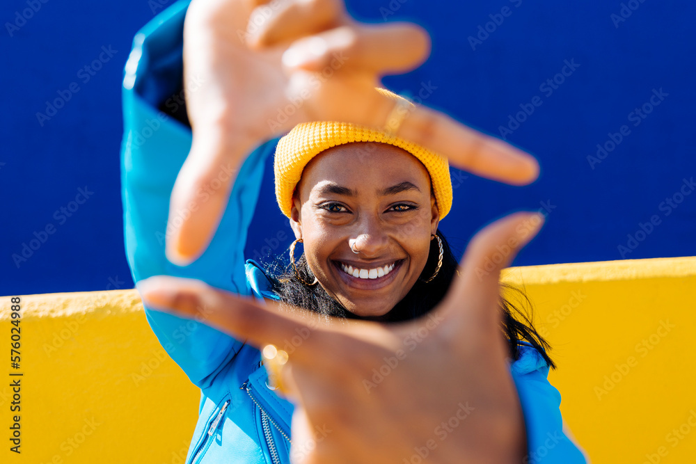 © VISTA by Westend61 - Happy woman making finger frame in front of two-tone color wall © VISTA by Westend61 - Happy woman making finger frame in front of two-tone color wall