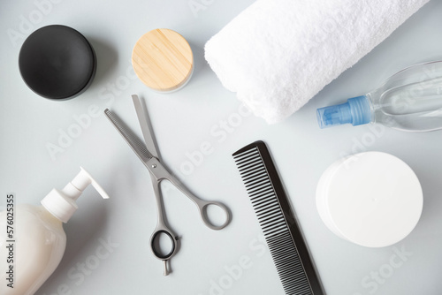 Hairbrush, filleting scissor and  other hairdressing salon accessories are on a grey background. View from the top point.