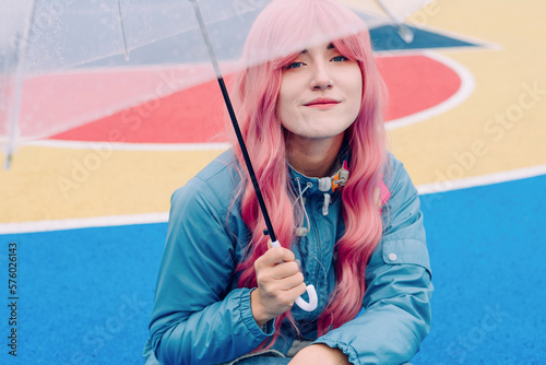 Smiling young woman with pink hair holding umbrella photo