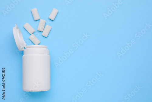Jar with chewing gums on light blue background, flat lay. Space for text