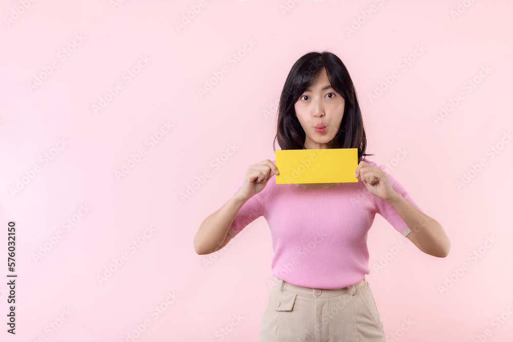 Portrait happy young woman model holding and showing blank space paper for advertisement information message poster with thumb up or point finger gesture isolated on pink pastel studio background. Portrait happy young woman model holding and showing blank space paper for advertisement information message poster with thumb up or point finger gesture isolated on pink pastel studio background.