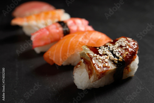 Delicious nigiri sushi on black table, closeup. Traditional Japanese cuisine