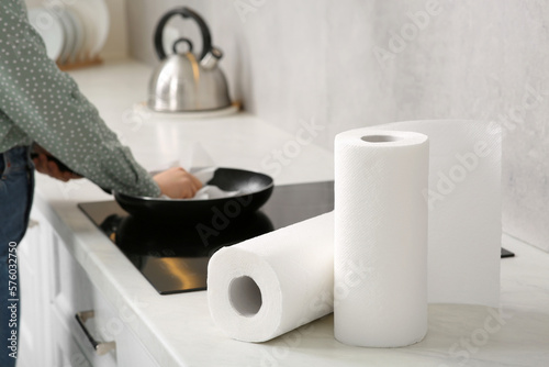 Woman wiping frying pan with paper towel in kitchen, selective focus. Space for text