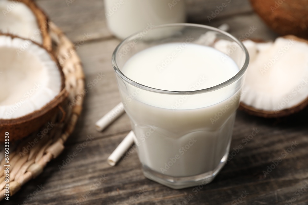 Glass of delicious vegan milk and coconuts on wooden table, closeup Glass of delicious vegan milk and coconuts on wooden table, closeup
