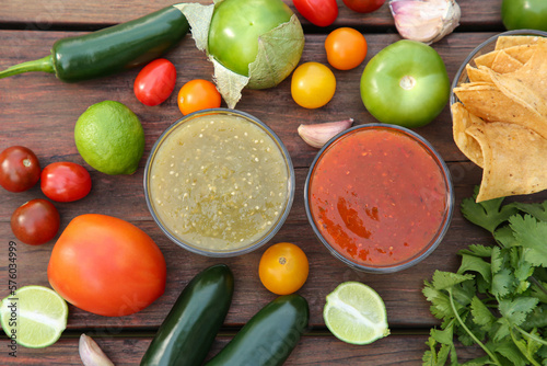 Flat lay composition of tasty salsa sauces and different ingredients on wooden table