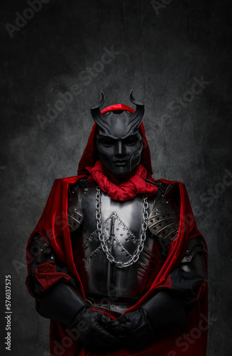 Fototapeta Naklejka Na Ścianę i Meble -  Studio shot of mystic prayer of dark cult dressed in silver plate armor and horned mask.