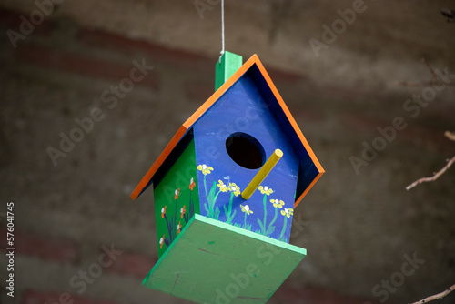 Colorful wooden birdhouse hanging on a rope.