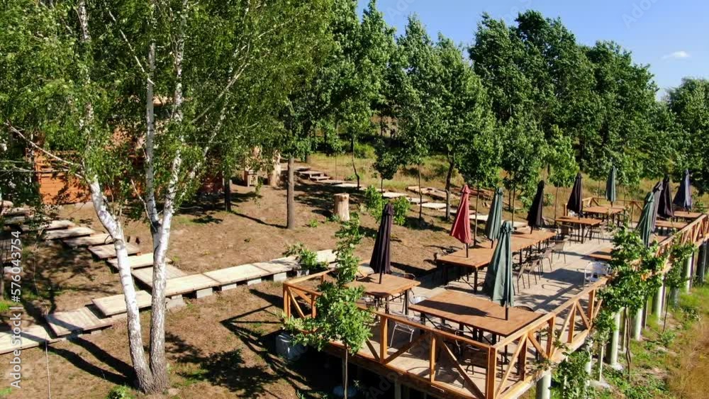 Panning aerial view of windy landscape in sunshine with wooden terrace. Outdoor cafe in sunbeam on summer spring day outdoors Panning aerial view of windy landscape in sunshine with wooden terrace. Outdoor cafe in sunbeam on summer spring day outdoors