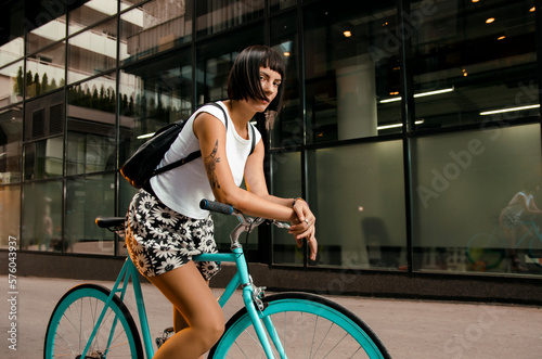 Beautiful hipster tattooed girl posing on vintage bike in urban environment 