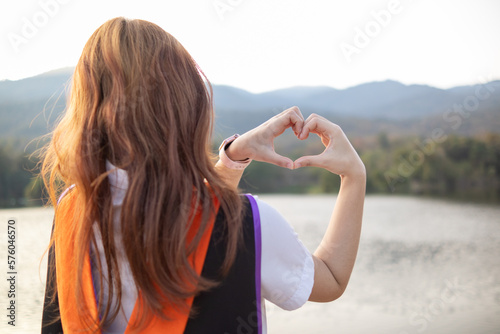Young woman shows her hands up to form heart symbol to show friendship love and kindness because heart is symbol of love. Young woman showing love with heart symbol from her hand