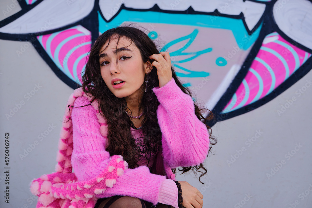 Fototapeta premium Teenage girl dressed in gothic style posing squatting on graffiti on a skateboarding rink
