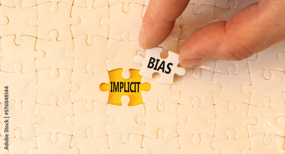 Implicit bias symbol. Concept words Implicit bias on white paper puzzles. Beautiful yellow table yellow background. Businessman hand. Business psychology implicit bias concept. Copy space. - obrazy, fototapety, plakaty 