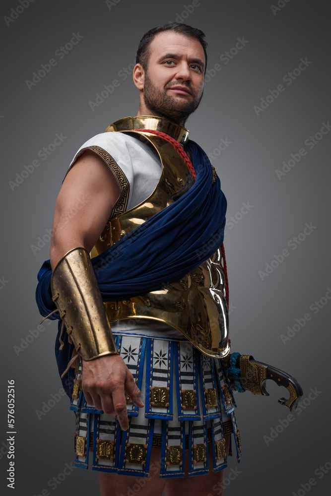 Φωτογραφία Studio shot of handsome greek warlord holding golden helmet against grey background
