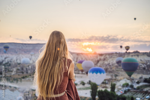 Tourist woman looking at hot air balloons in Cappadocia, Turkey. Happy Travel in Turkey concept. Woman on a mountain top enjoying wonderful view