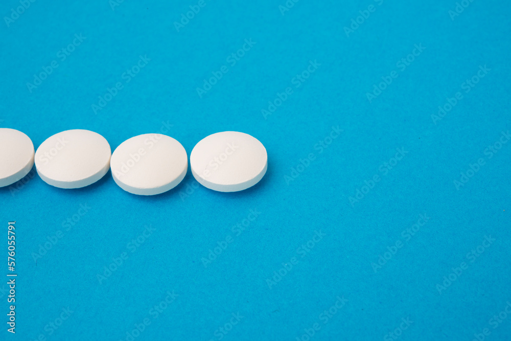 White round pills on blue textured background White round pills on blue textured background