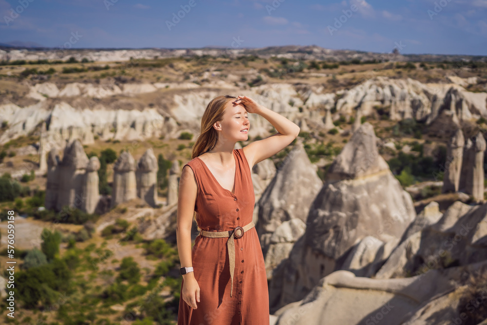 Naklejka premium Young woman exploring valley with rock formations and fairy caves near Goreme in Cappadocia Turkey