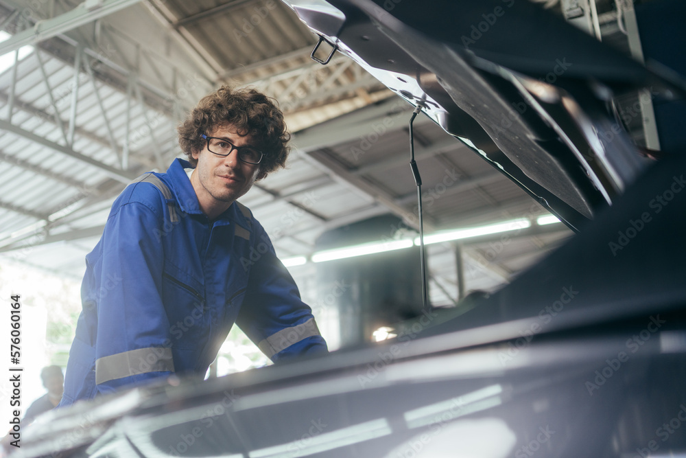 Caucasian auto mechanic man checking and repairing car radiator bonnet in automotive in garage at auto repair shop, motor technician working after vehicle service maintenance concept