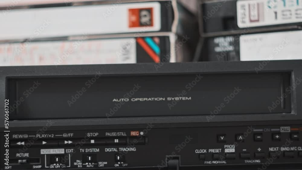 Male hand inserts VHS cassette into a VCR Video recorder. Black vintage