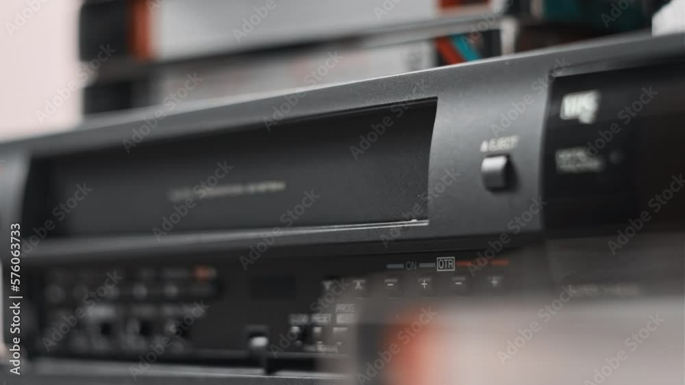Eject VHS tape cassette from VCR player. Male hand pulls out VHS from a