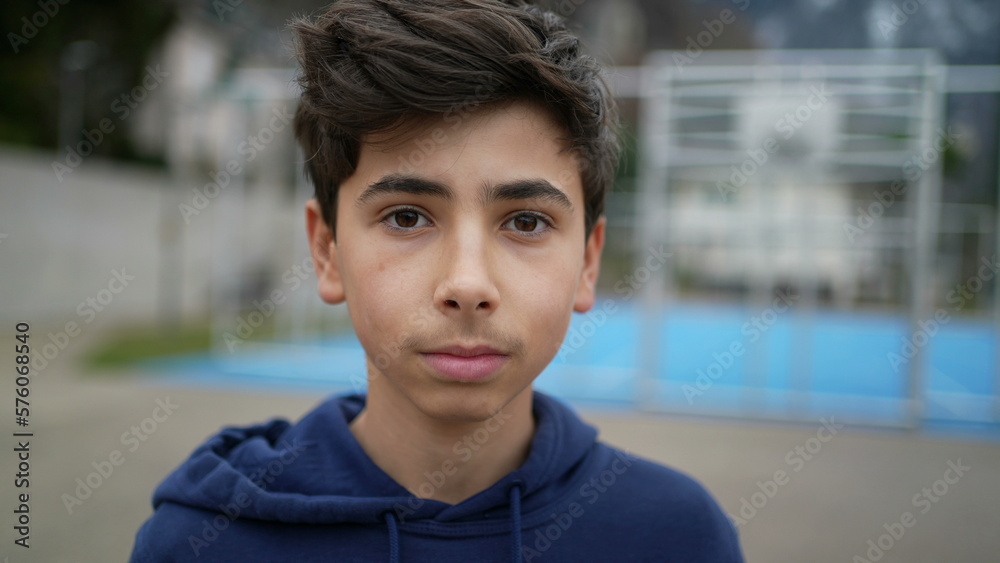 One portrait of a teen young boy closeup face standing outside at city park. Handsome male teenager looking at camera One portrait of a teen young boy closeup face standing outside at city park. Handsome male teenager looking at camera