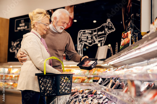 Foto An old couple is buying fresh packed meat at butchery in supermarket