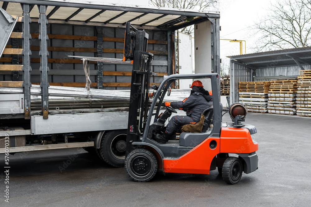 Forklift loader in the metal warehouse. Loading and unloading stainless metal pipes Forklift loader in the metal warehouse. Loading and unloading stainless metal pipes