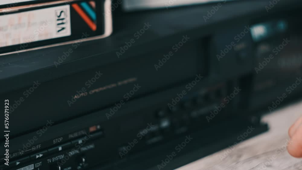 Eject VHS tape cassette from VCR player. Male hand pushes a button and