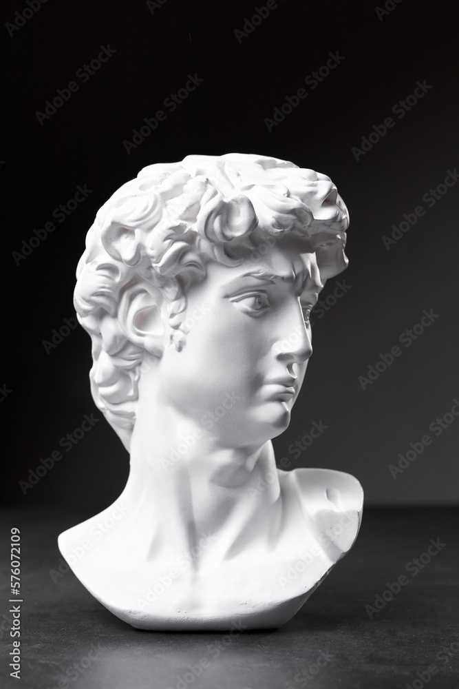 Gypsum statue of David's head. Michelangelo's David statue plaster copy on dark background. Ancient italian sculpture, statue of hero Gypsum statue of David's head. Michelangelo's David statue plaster copy on dark background. Ancient italian sculpture, statue of hero