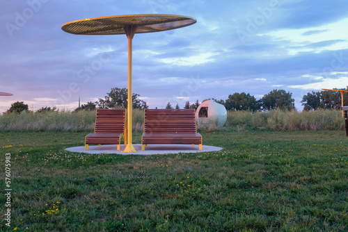 Two park lounge chair and one umbrella with sun setting on the side