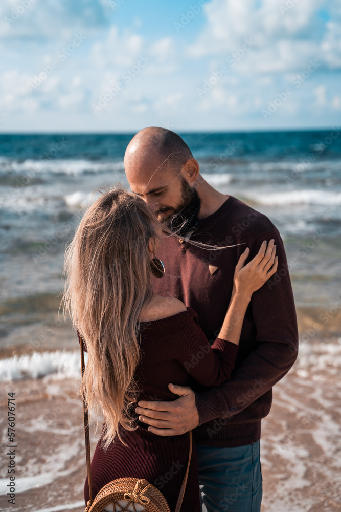 A couple in love on the beach or ocean. Photo against the background of water and the horizon. Young family on a walk along the sandy coast on a pleasant sunny day. Relations between a man and a woman