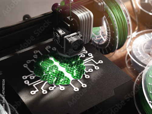 symbolic brain sculpture is made by a 3d printer from green filament in vivid light. filament rolls on wooden desk in background. selective focus on print head. ecological intelligence concept photo