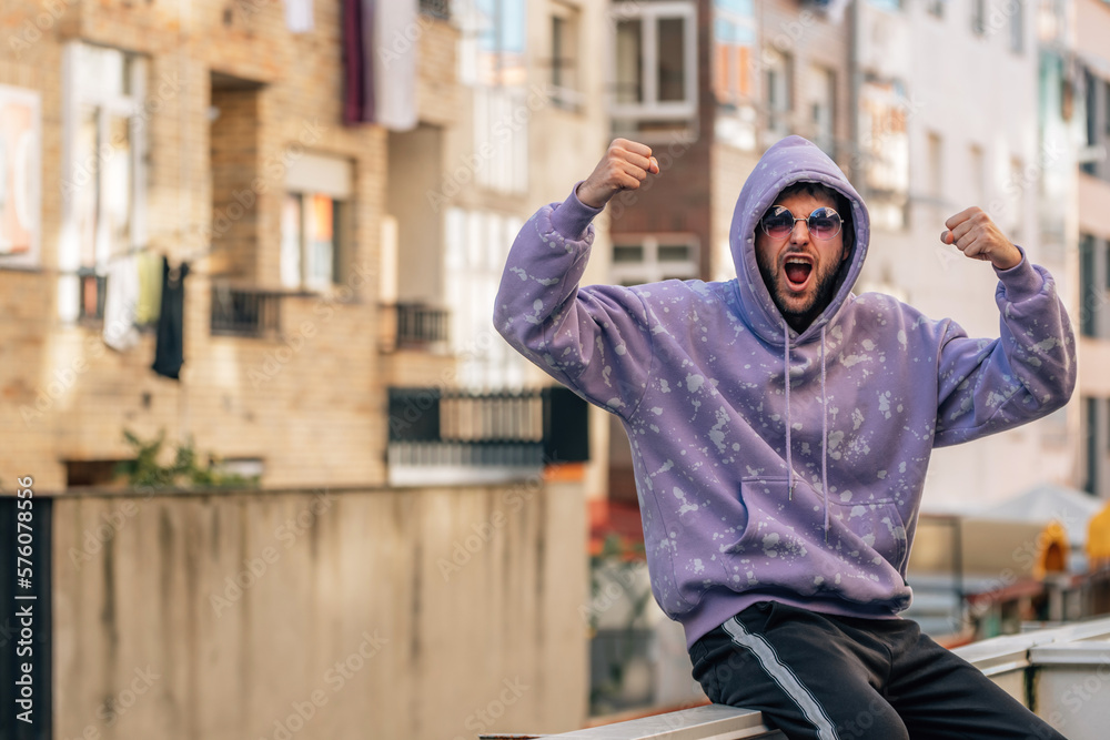 young man on the street in sportswear celebrating euphoric